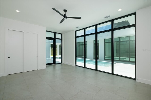 unfurnished room featuring floor to ceiling windows, ceiling fan, and light tile patterned floors