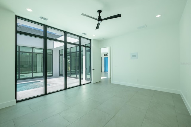 tiled spare room with ceiling fan and a wall of windows