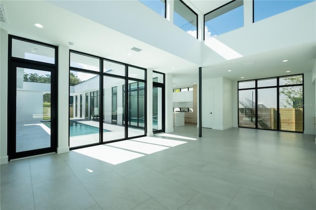 tiled spare room featuring floor to ceiling windows and a high ceiling