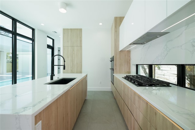 kitchen featuring light stone countertops, sink, backsplash, white cabinets, and black appliances