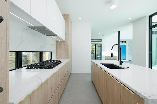 kitchen featuring backsplash, sink, light tile patterned floors, white cabinets, and stainless steel gas stovetop