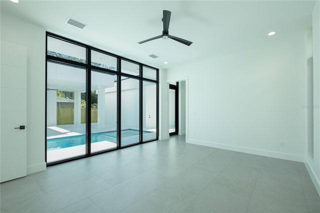 tiled empty room with ceiling fan and expansive windows