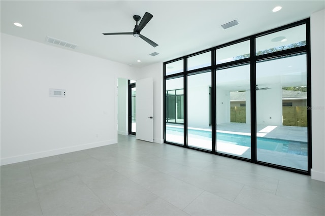 tiled empty room featuring ceiling fan and expansive windows