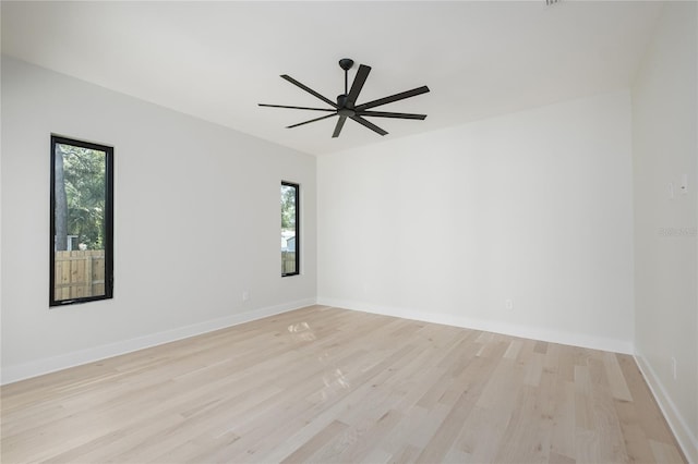 spare room featuring light wood-style floors, a wealth of natural light, baseboards, and a ceiling fan