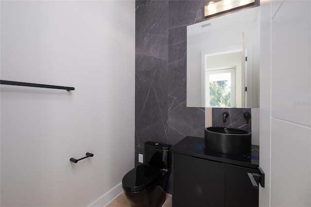 half bath with vanity, backsplash, toilet, and baseboards