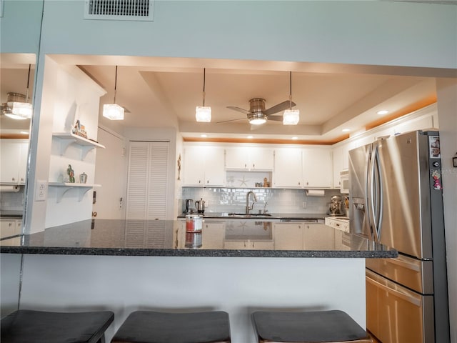 kitchen featuring pendant lighting, ceiling fan, dark stone countertops, tasteful backsplash, and stainless steel refrigerator with ice dispenser