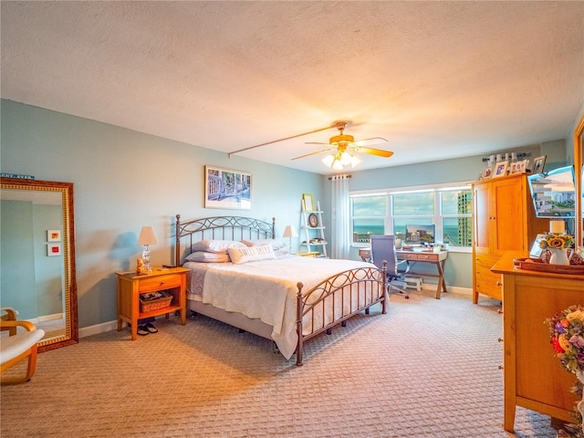 bedroom featuring light colored carpet, ceiling fan, and a textured ceiling