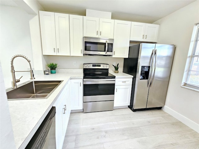 kitchen with white cabinetry, appliances with stainless steel finishes, sink, and light wood-type flooring