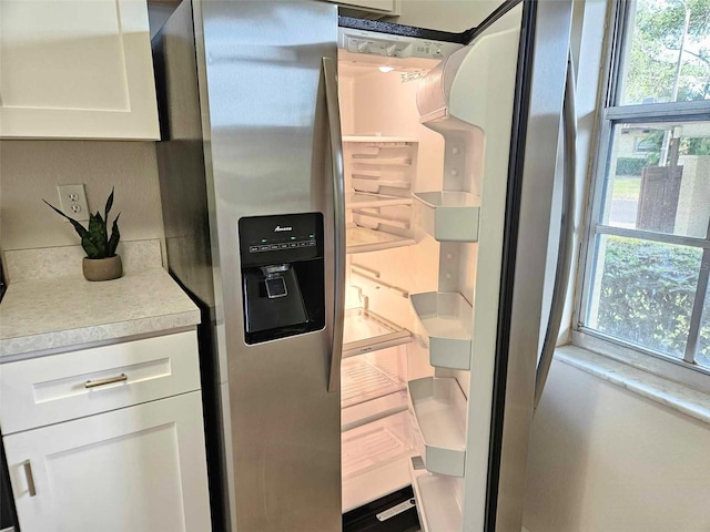 interior space featuring stainless steel fridge and white cabinets