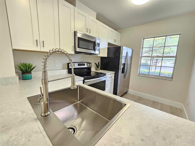 kitchen with white cabinetry, appliances with stainless steel finishes, sink, and light hardwood / wood-style flooring