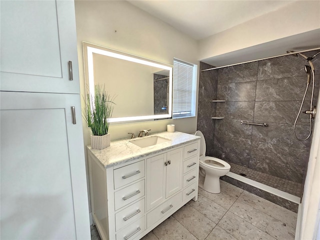 bathroom featuring a tile shower, vanity, tile patterned flooring, and toilet