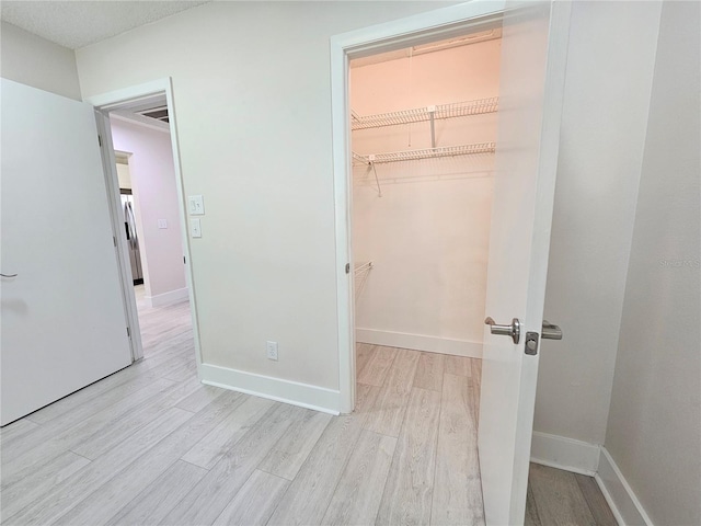 unfurnished bedroom featuring a walk in closet, light wood-type flooring, and a closet