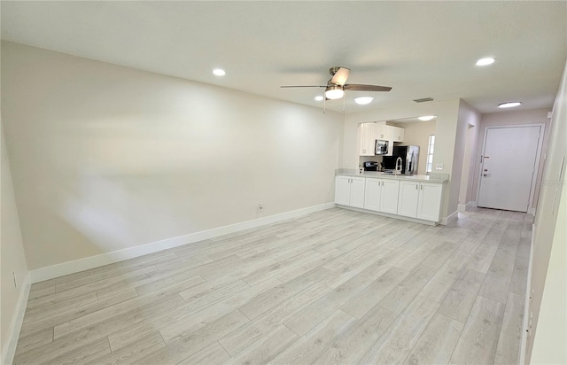 unfurnished living room featuring ceiling fan and light hardwood / wood-style flooring