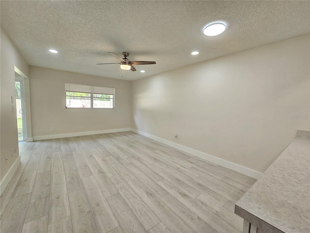 spare room with ceiling fan, a textured ceiling, and light hardwood / wood-style flooring