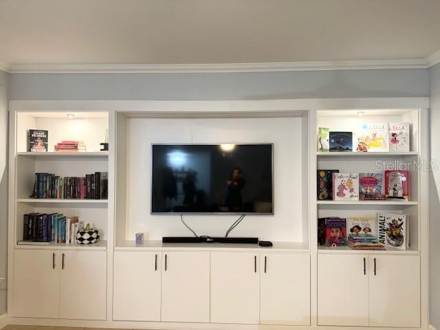 living room featuring ornamental molding and built in shelves