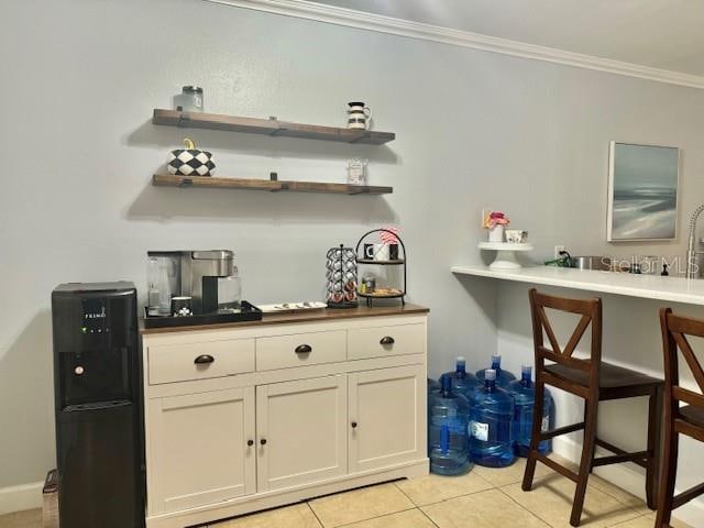 bar with light tile floors, white cabinets, and crown molding