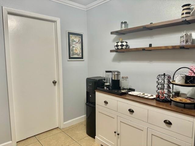 kitchen featuring crown molding, white cabinets, and light tile floors