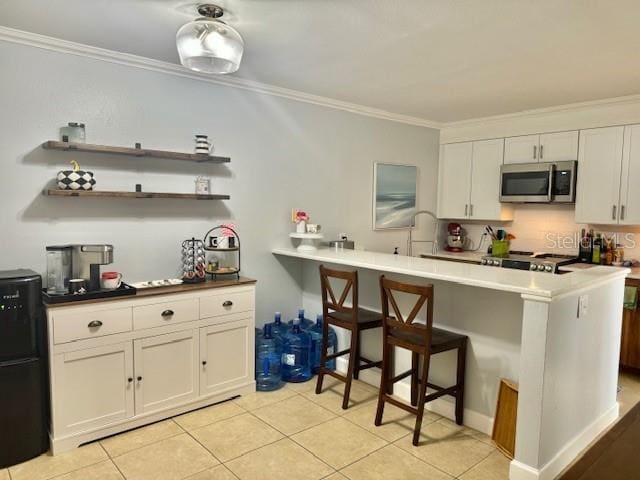 kitchen with kitchen peninsula, white cabinetry, light tile flooring, stove, and crown molding