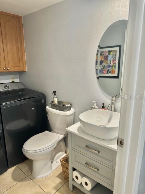 bathroom featuring vanity, tile flooring, washer / dryer, and toilet