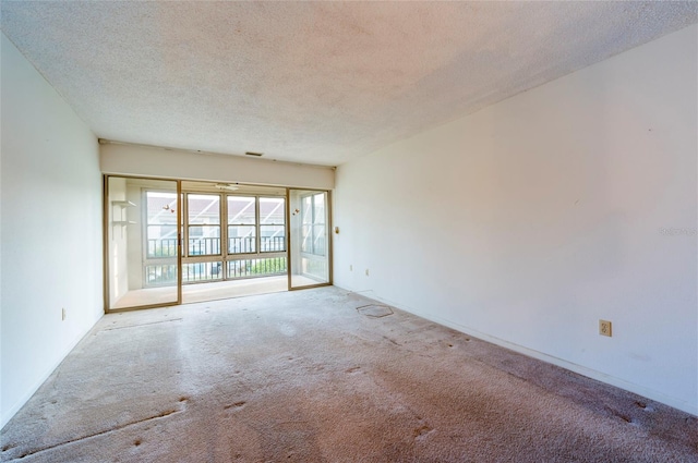 empty room with a textured ceiling and light colored carpet