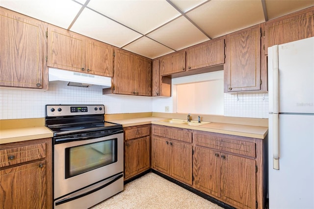 kitchen with sink, white refrigerator, stainless steel electric stove, backsplash, and a drop ceiling