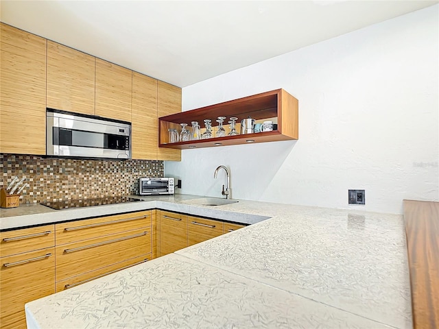 kitchen with black electric stovetop, backsplash, and sink