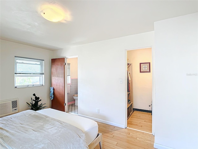 bedroom featuring connected bathroom and light hardwood / wood-style flooring