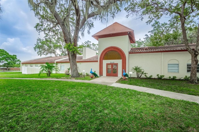 mediterranean / spanish home with french doors and a front lawn