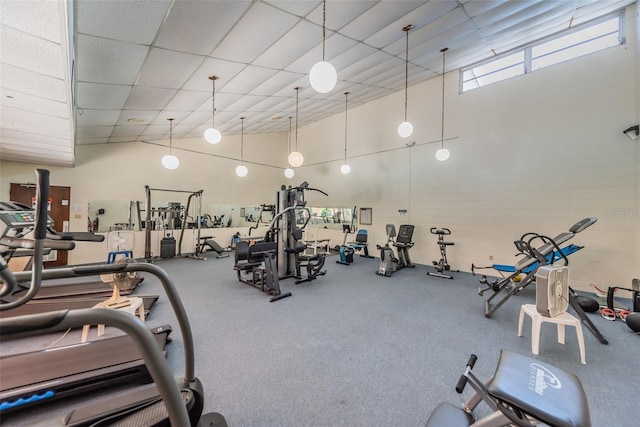 exercise room with a towering ceiling and a paneled ceiling