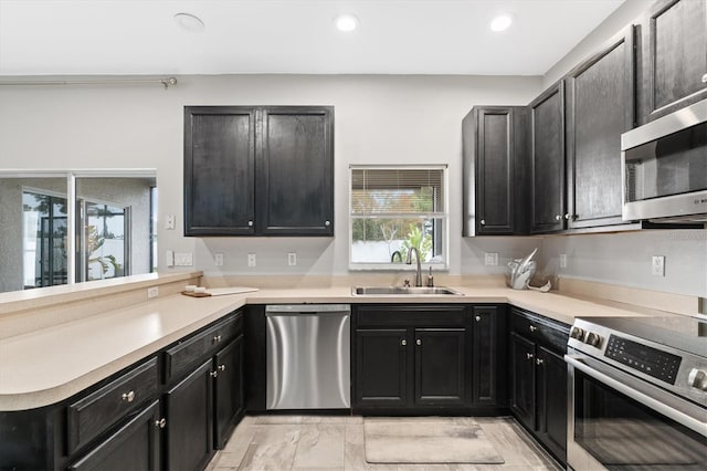 kitchen with light tile floors, appliances with stainless steel finishes, kitchen peninsula, and sink