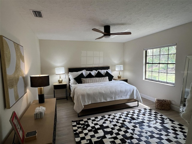 bedroom with a textured ceiling, ceiling fan, and dark hardwood / wood-style flooring