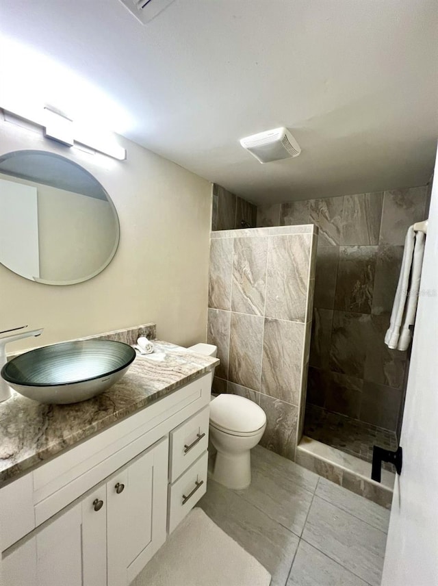 bathroom featuring vanity, tile walls, tile floors, tiled shower, and toilet