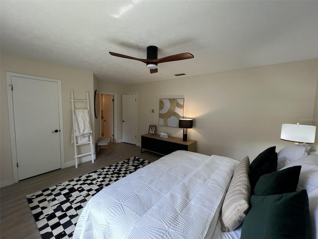 bedroom featuring a textured ceiling, ceiling fan, and dark hardwood / wood-style floors