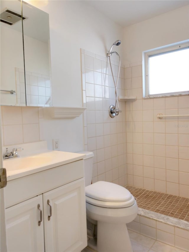 bathroom with vanity, toilet, and a tile shower