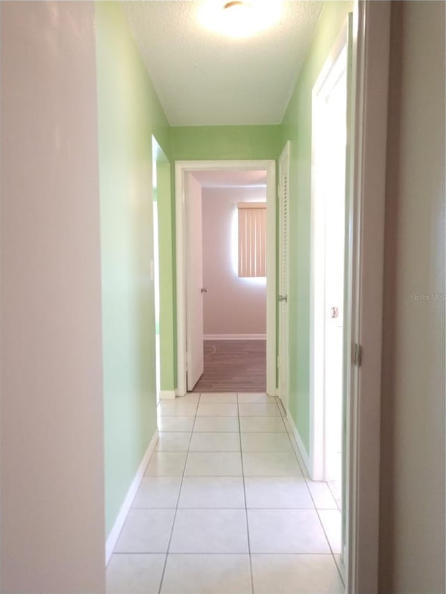 corridor with light tile patterned floors and a textured ceiling