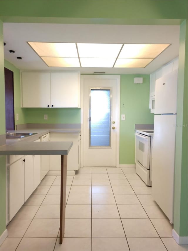 kitchen with white cabinetry, light tile patterned flooring, white appliances, and kitchen peninsula