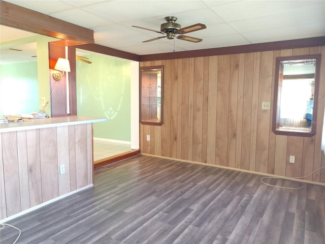 empty room featuring dark wood-style flooring, wooden walls, and baseboards