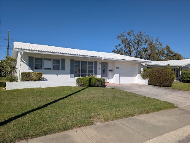 ranch-style home featuring an attached garage, a tiled roof, a front lawn, and stucco siding