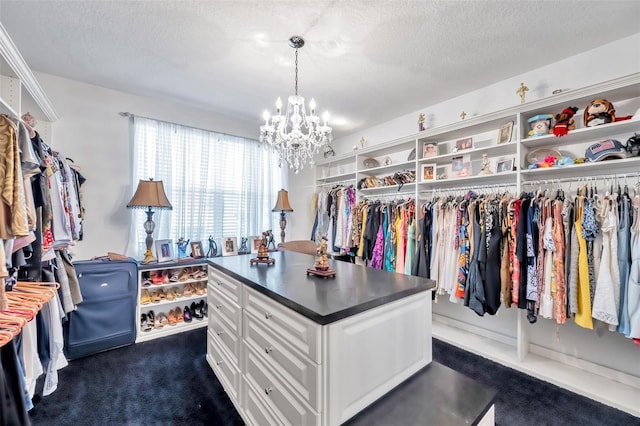 walk in closet featuring dark carpet and a notable chandelier