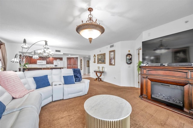 living room featuring an inviting chandelier, visible vents, and carpet flooring