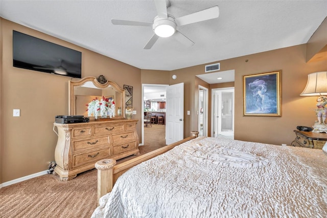 carpeted bedroom featuring visible vents, ceiling fan, ensuite bath, and baseboards