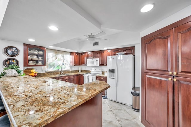 kitchen featuring light stone counters, glass insert cabinets, a sink, white appliances, and a peninsula