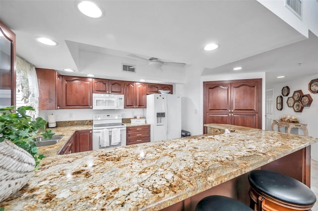 kitchen featuring light stone counters, white appliances, and visible vents