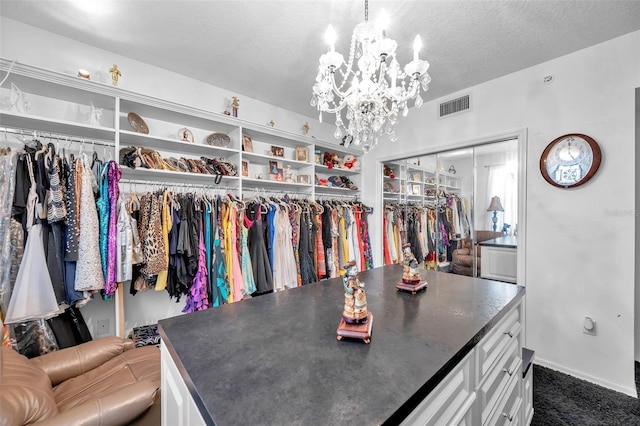 walk in closet with visible vents, dark carpet, and a notable chandelier