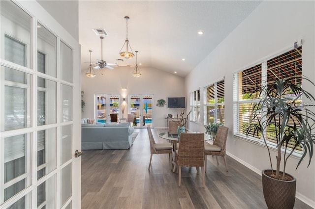 dining space with baseboards, visible vents, wood finished floors, french doors, and high vaulted ceiling