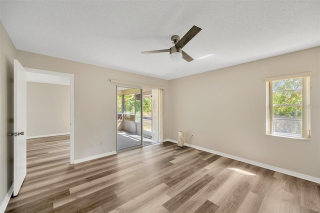 spare room with light wood-type flooring, a textured ceiling, and ceiling fan