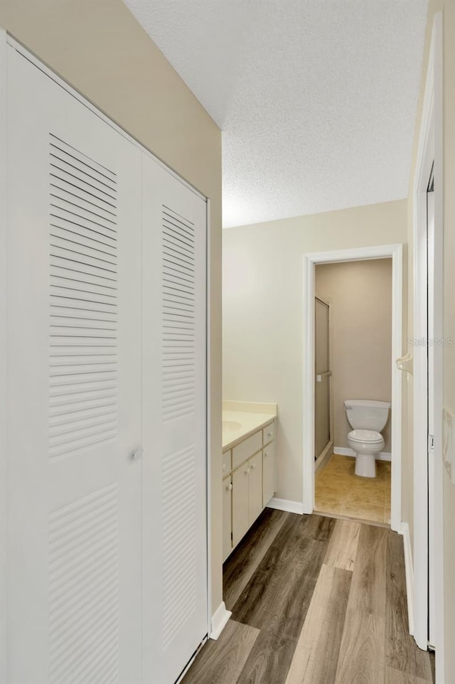 bathroom featuring vanity, hardwood / wood-style flooring, a textured ceiling, and toilet