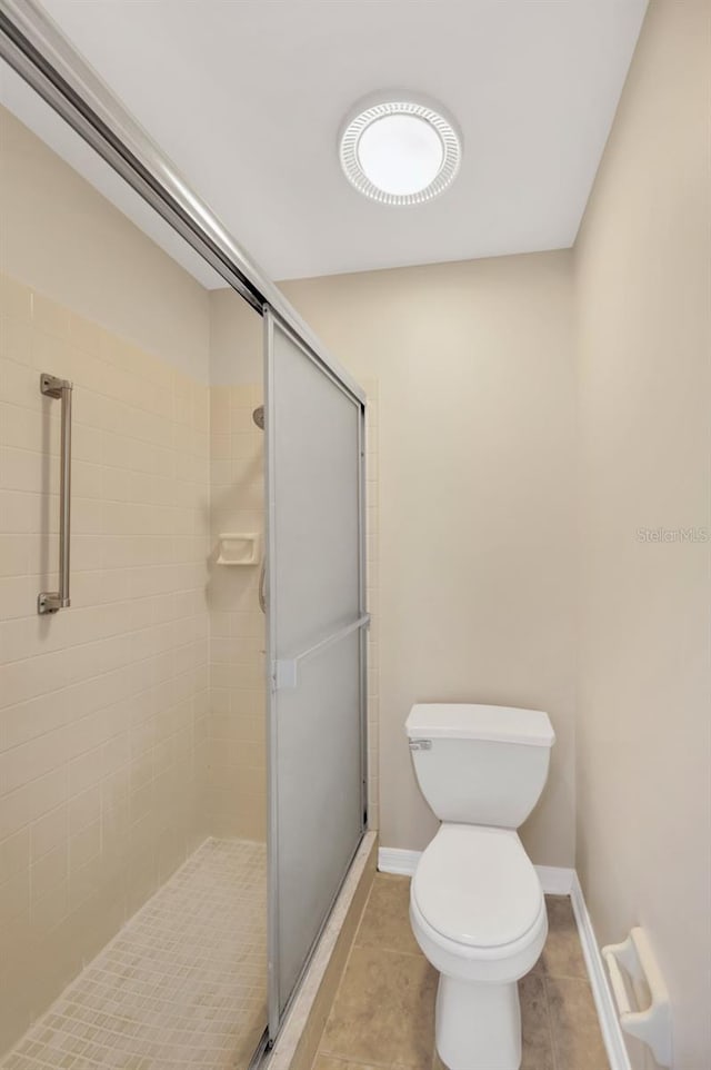 bathroom with tile patterned flooring, toilet, and an enclosed shower