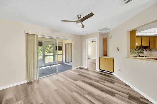 unfurnished living room with a textured ceiling, sink, ceiling fan, and light hardwood / wood-style flooring