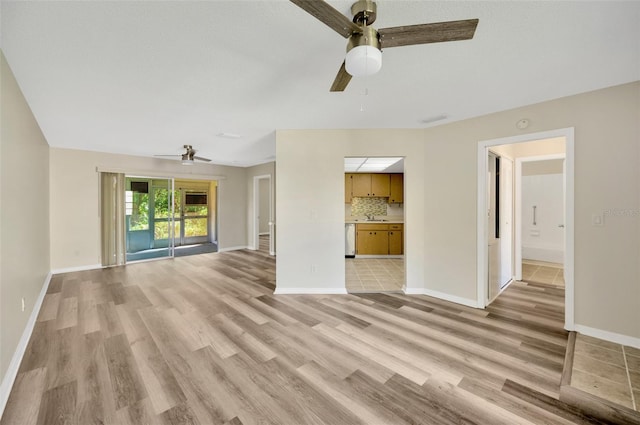 unfurnished living room with ceiling fan, sink, and light wood-type flooring